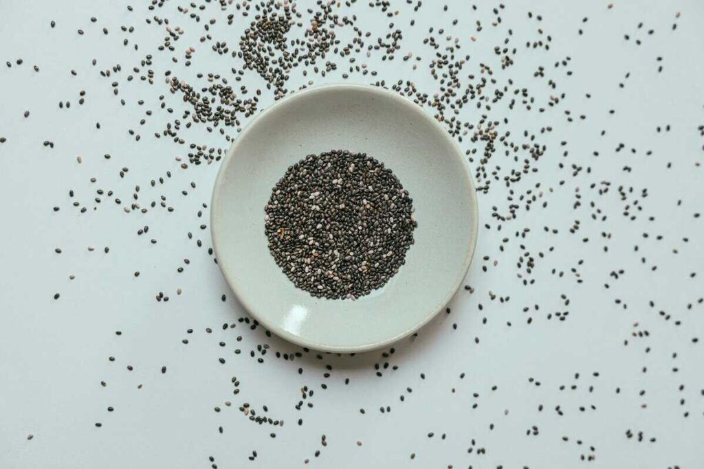 small bowl of chia seeds with measuring spoon for daily intake