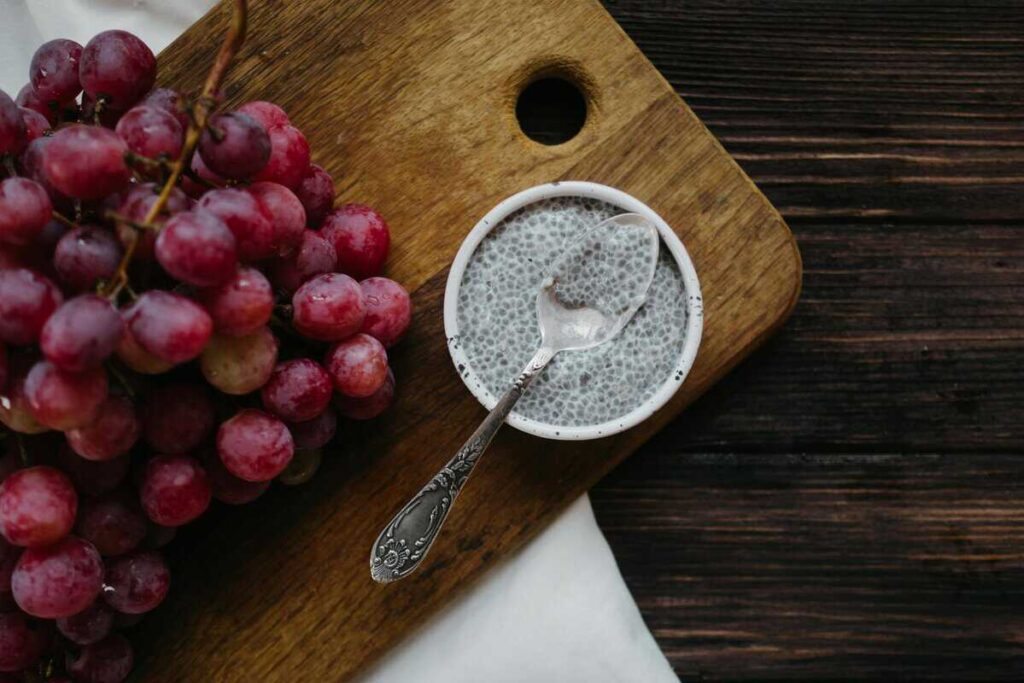 Glass of chia seed water with fresh berries and lemon, served on a wooden table